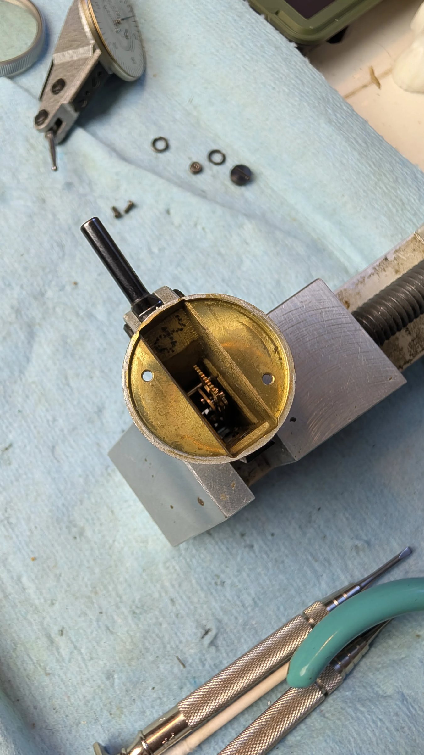 Bench context: indicator body held in vise, dial and hardware removed alongside